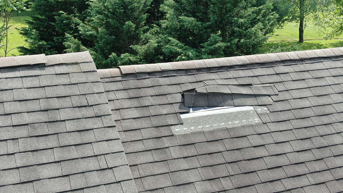Missing shingles around a skylight on a residential roof—typical storm damage that can lead to leaks if left untreated