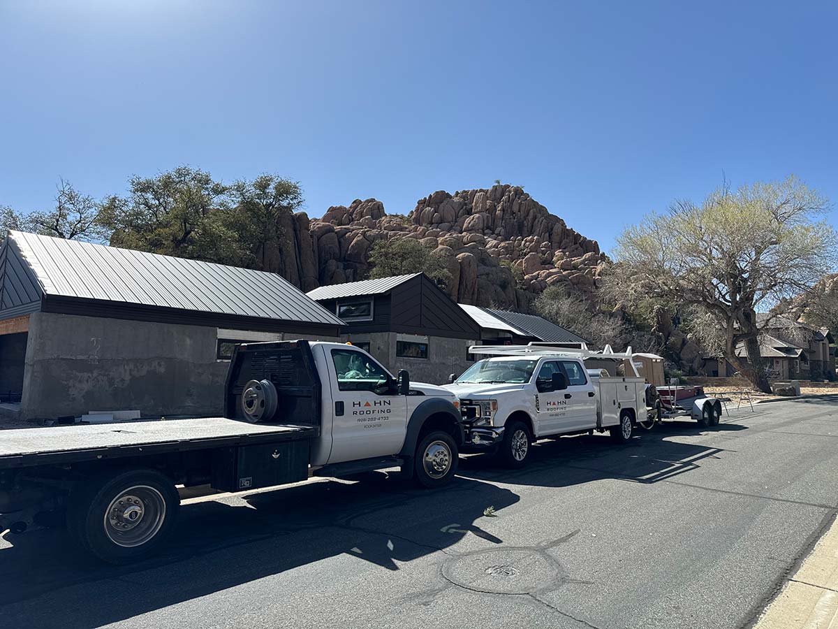 Hahn Roofing trucks on site for a roof inspection in Northern Arizona, with metal roofs and red rock views in the background