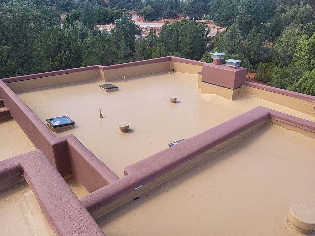 Flat roofs in Arizona with tan coating and red parapets, built to withstand regional heat and rainfall