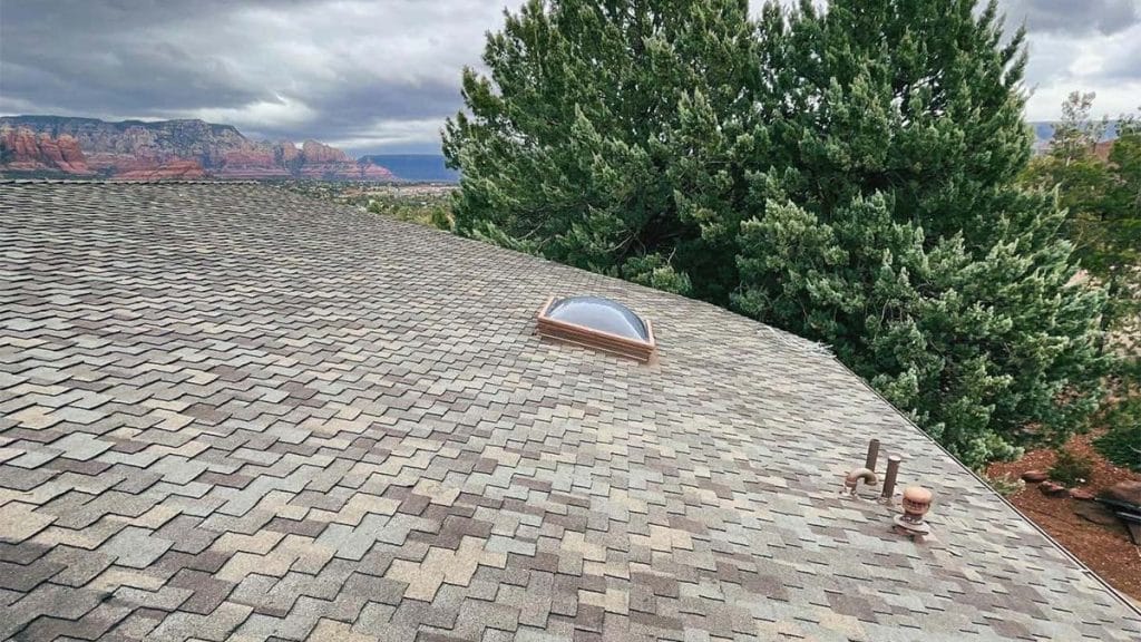 Roof with grey architectural roofing shingles and a skylight in Sedona, highlighting Hahn Roofing's quality work with Sedona's landscape.