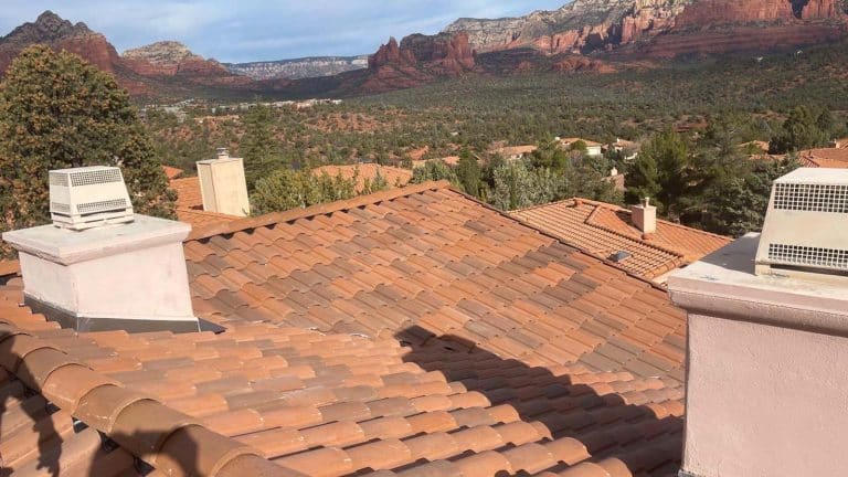 Terracotta tile roof with chimneys against Sedona's iconic red rock backdrop, showcasing roofing in Northern Arizona. Image for blog post "5 Common Roofing Mistakes Prescott Homeowners Make" by Hahn Roofing.