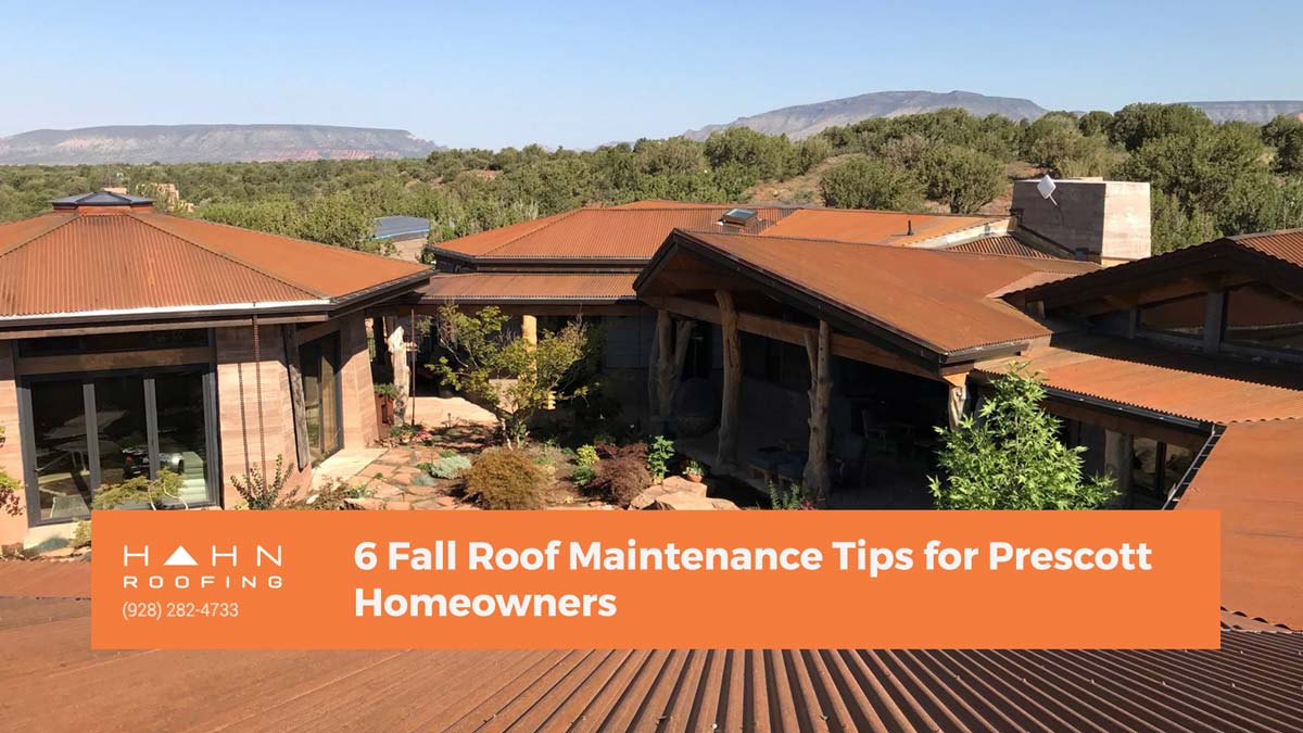 A rustic Prescott home featuring a metal roof, surrounded by lush greenery and hills in the background. Related to Hahn Roofing's "6 Fall Roof Maintenance Tips for Prescott Homeowners."