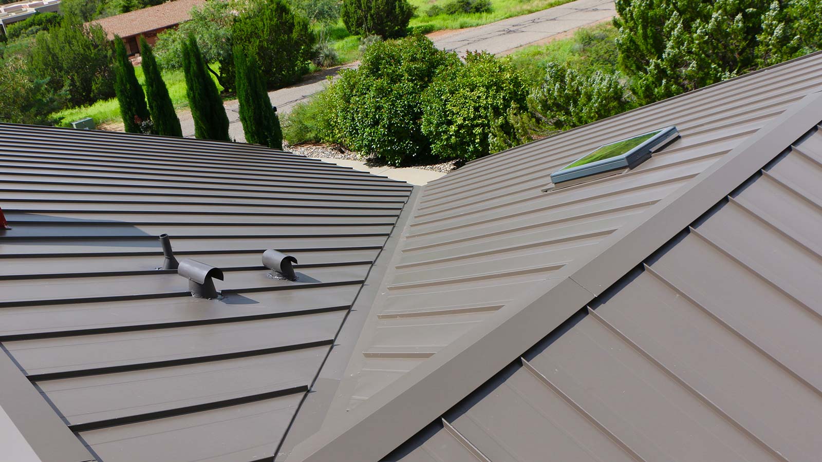 A sleek West Sedona home with gray metal roofing surrounded by greenery. Featuring Hahn Roofing's "Choosing the Right Roof Color for Your West Sedona Home: Aesthetics and Energy Efficiency."