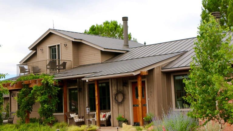 A charming Cottonwood home with a metal roof, surrounded by vibrant landscaping. Highlighting Hahn Roofing's "Essential Maintenance Tips for Cottonwood Homeowners."