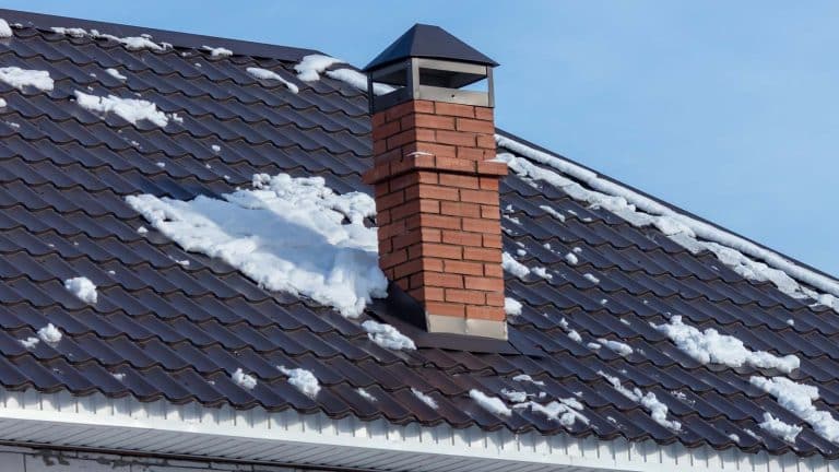 A snowy roof with a red brick chimney in Sedona, highlighting essential winter preparation tips. From the blog post "How to Prepare Your Roof for Winter in Sedona" by Hahn Roofing.