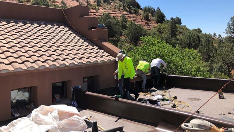 A team of roofers working on a tile roof with Camp Verde's natural landscape in the background. From the blog post "Spring Roofing Checklist for Camp Verde, AZ" by Hahn Roofing.