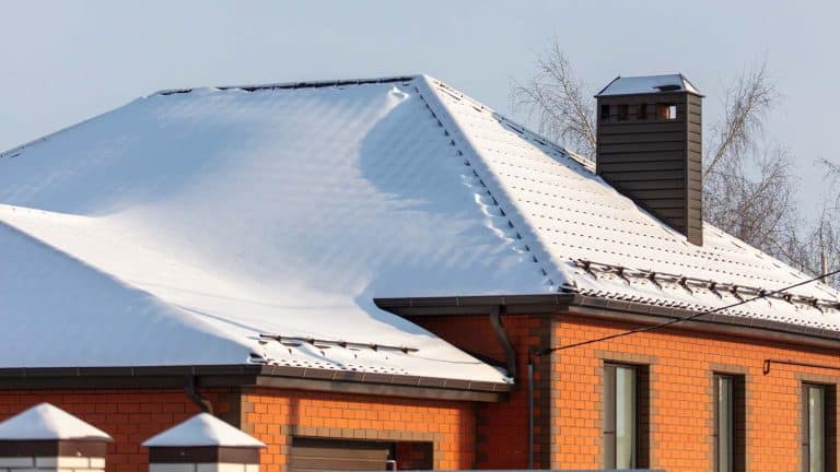 A snow-covered roof with a chimney in Cottonwood, illustrating winter roofing challenges. From the blog post "Top 5 Winter Roofing Problems to Watch for in Cottonwood" by Hahn Roofing.