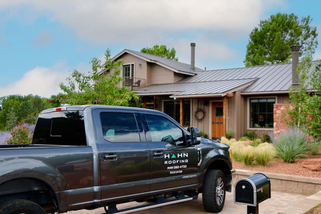 A Hahn Roofing truck parked in front of a roof installation job site in Cottonwood, AZ